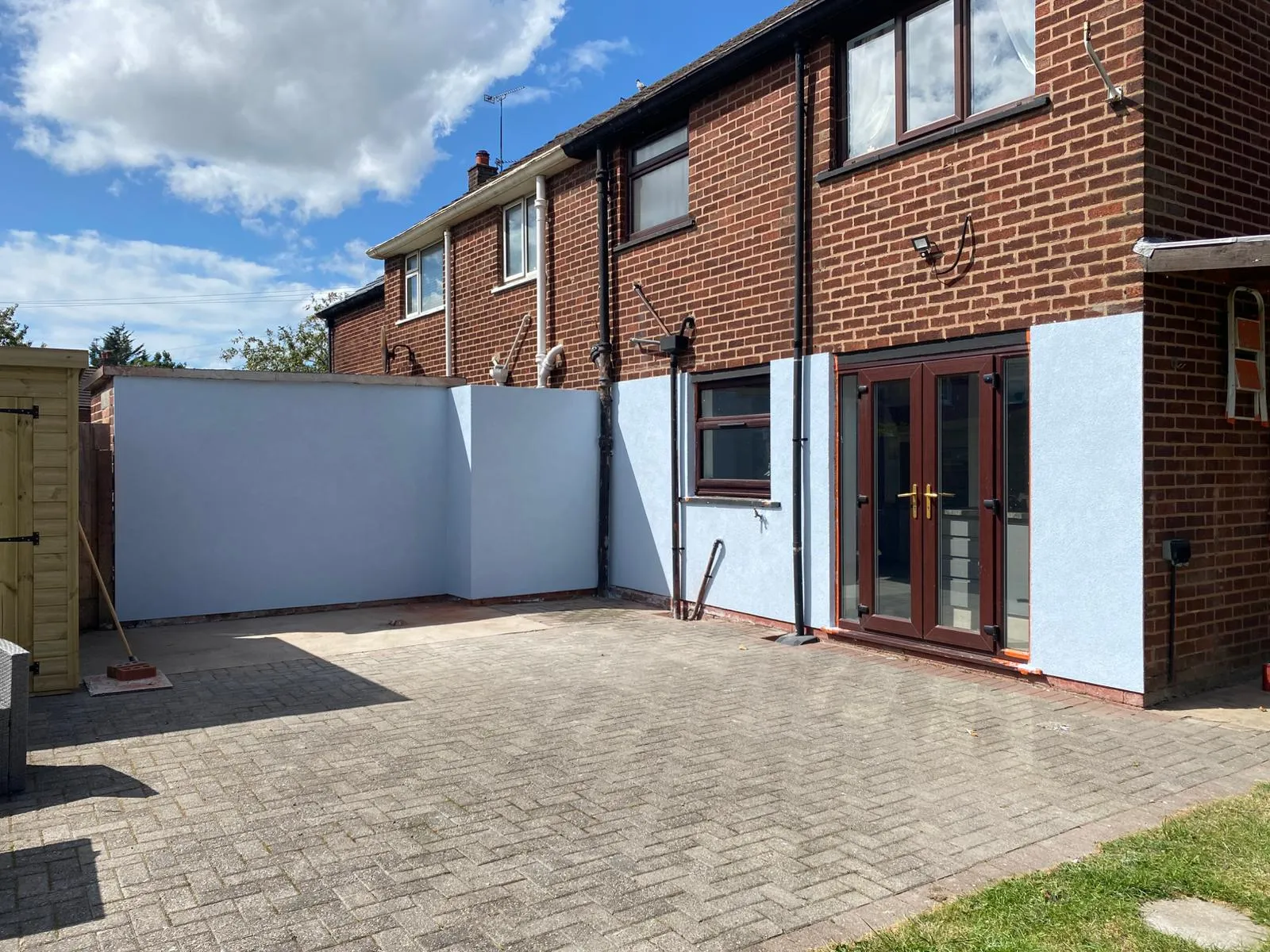A house with a brick patio and a white fence.