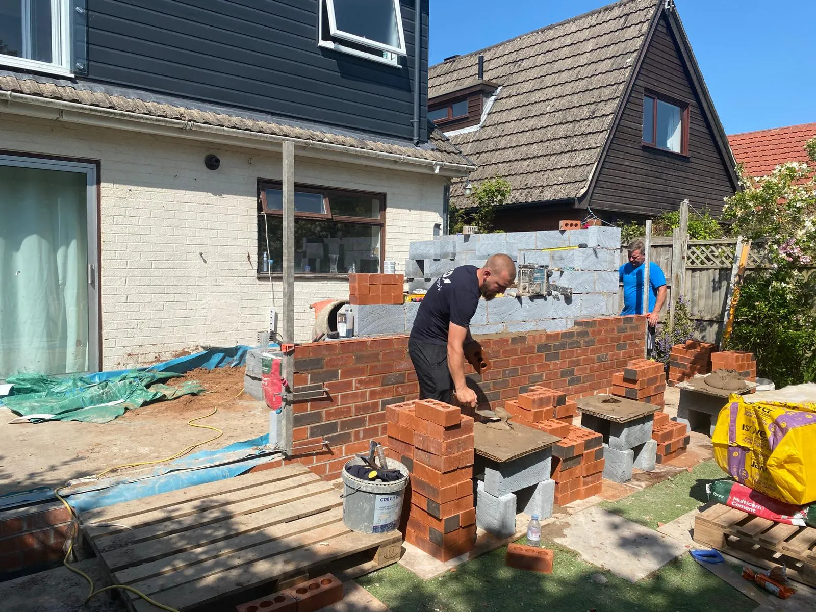 A man is working on a brick wall.